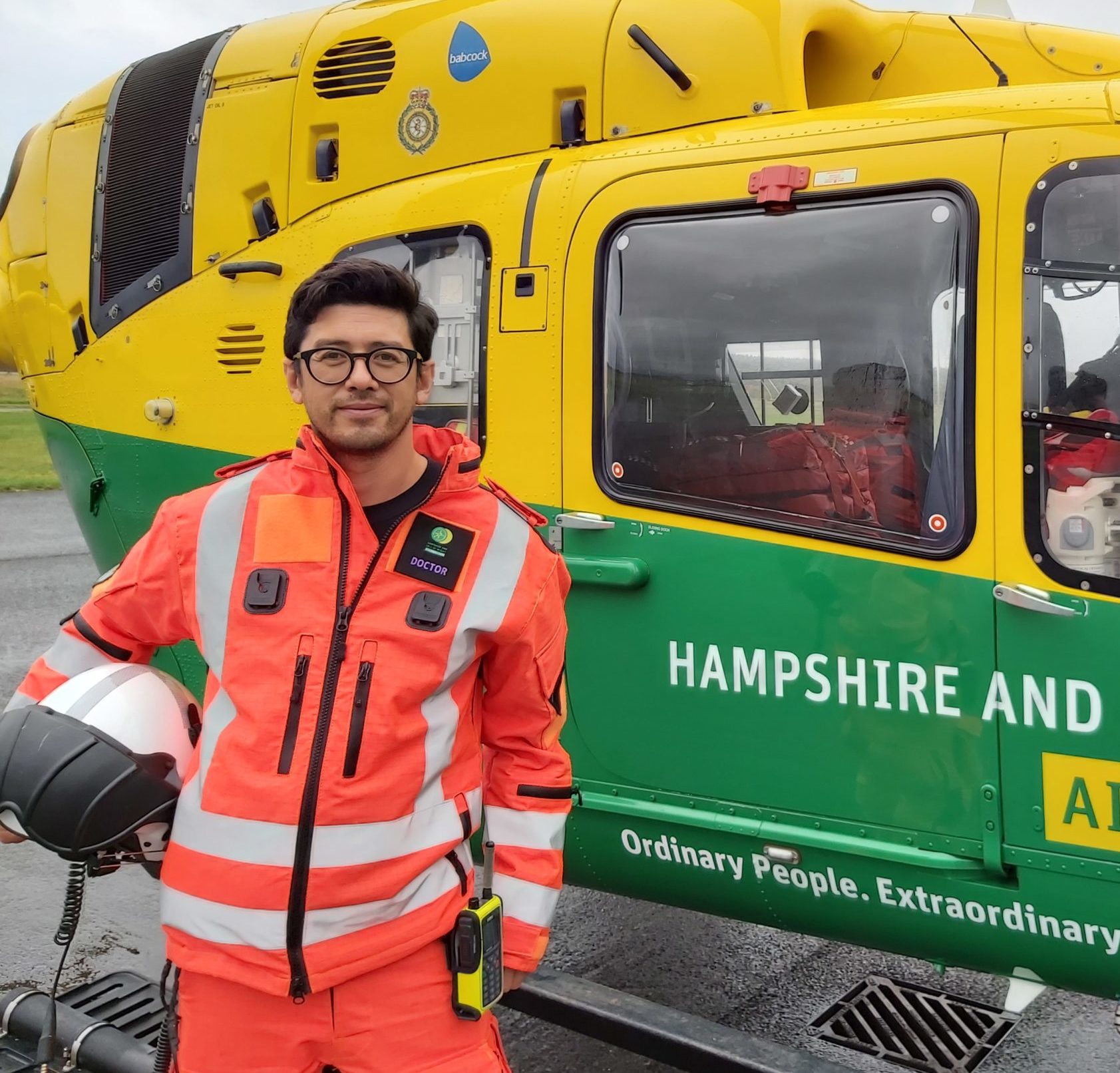 Dr Chris Beng is standing in front of the helicopter in his flight suit